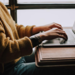 Person in yellow sweater sitting at a desk reviewing a real-time dashboard for business insights